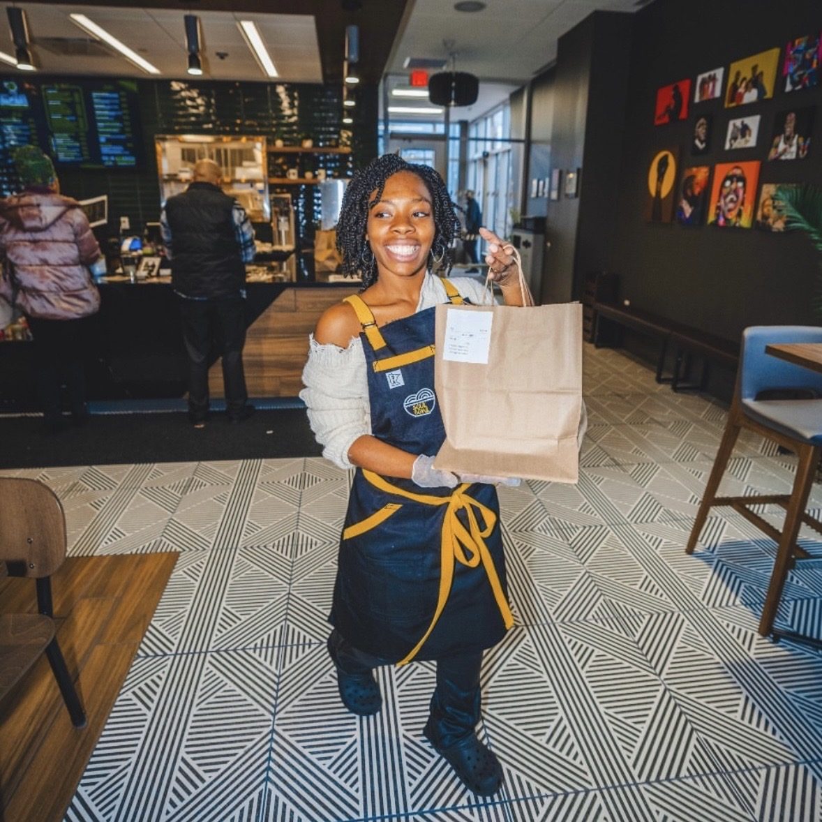 A smiling Soul Bowl employee holding a takeout order